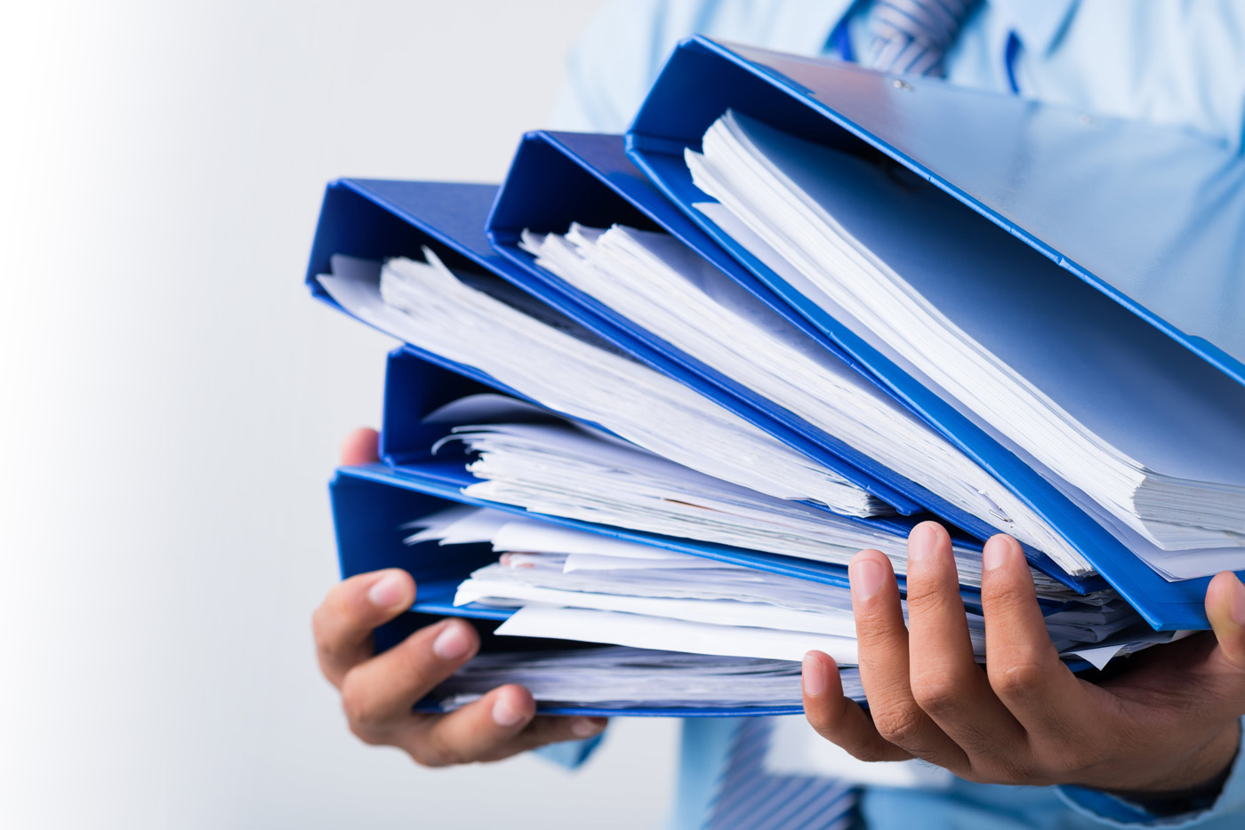 A persons holding a stack of binders